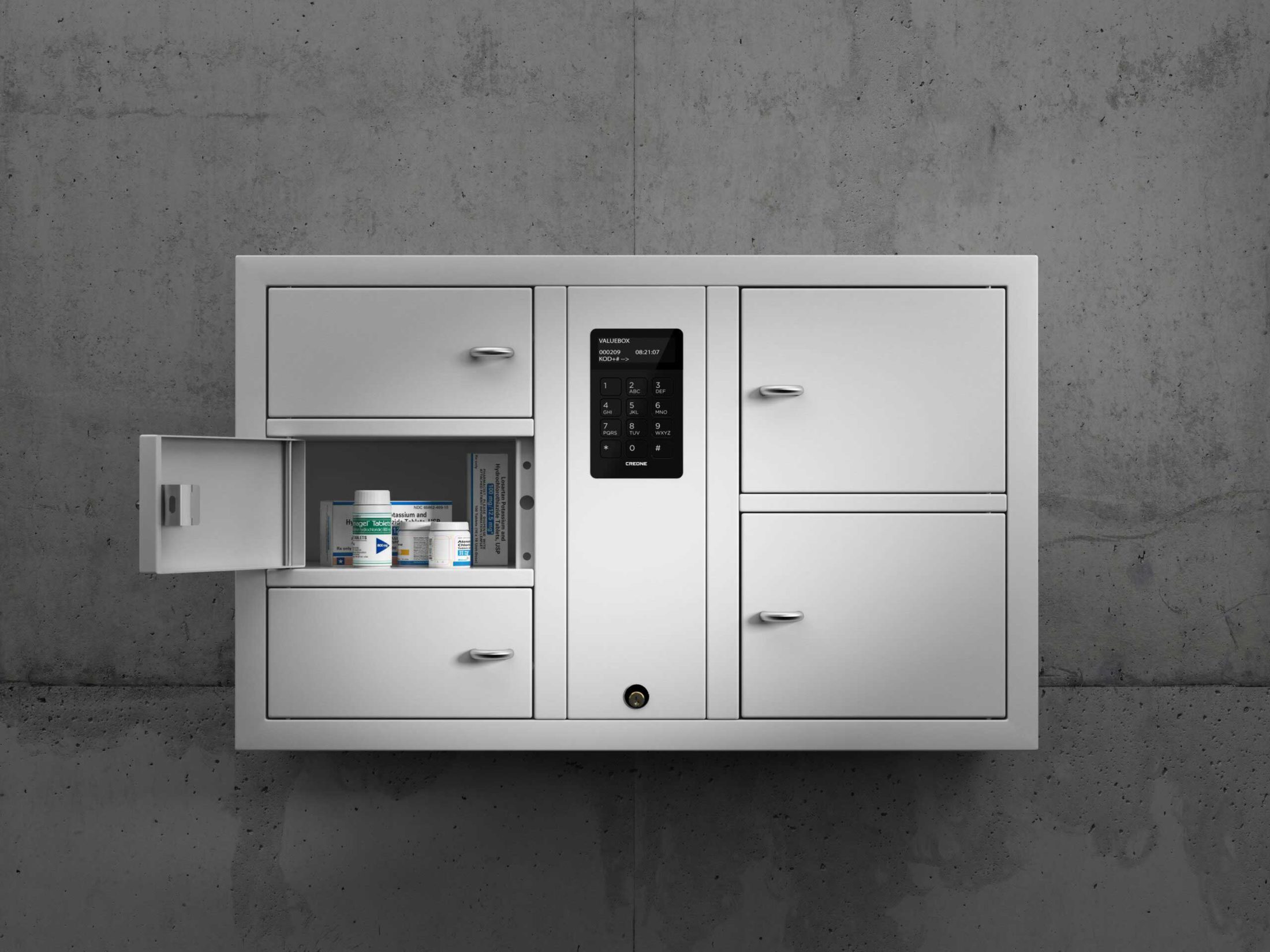Gabinete para objetos de valor 7005 S de la serie System. Montado en la pared con compartimentos abiertos que contienen medicamentos para su recogida.